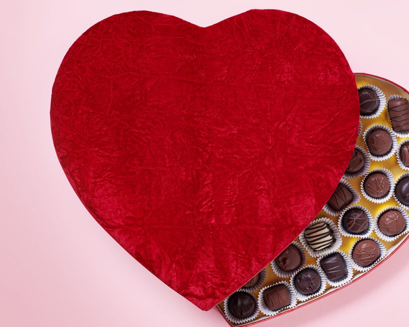 Chocolates in a red, heart-shaped box on a pick background