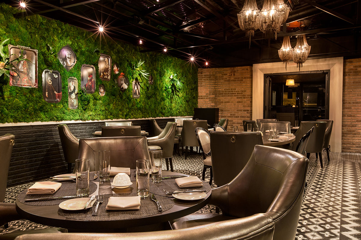 A green living wall with tables and chairs beside it