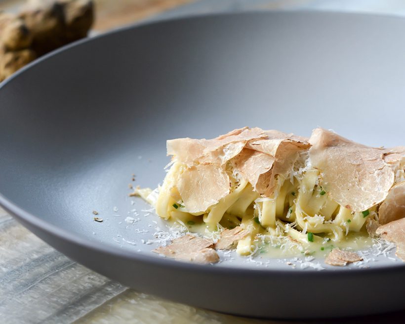 Pasta topped with truffles in a grey bowl