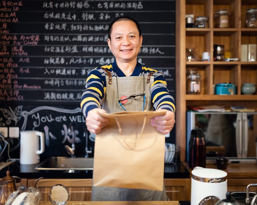 Waiter handing a bag of take out food