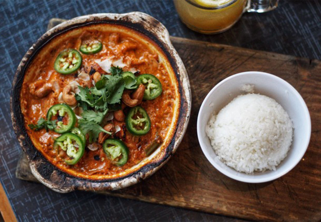 A bowl of seafood stew next to a bowl of rice.