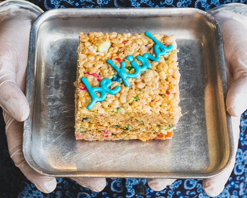 A crispy rice cereal treat that says "be kind" in frosting
