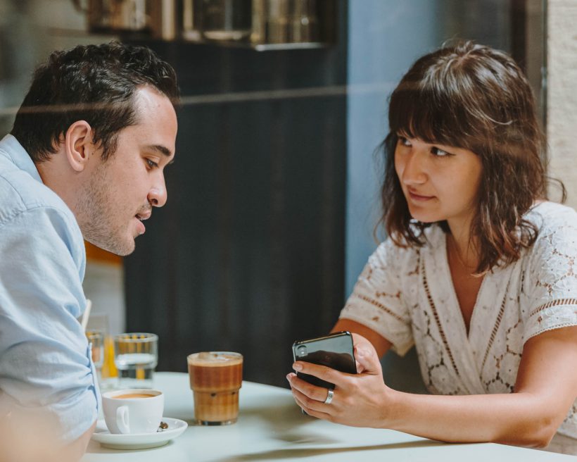 Two people look at a phone at a table