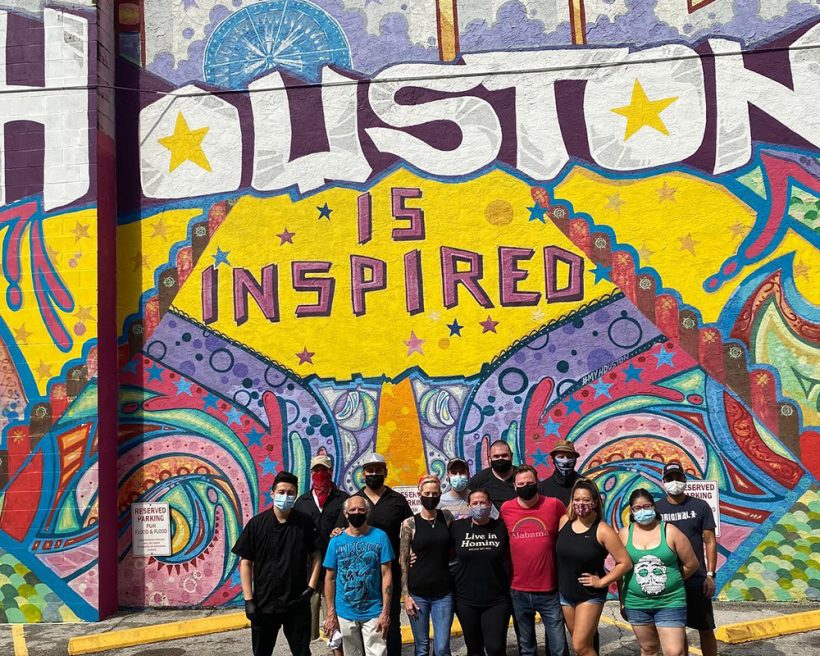 Houston restaurant workers take a photo in front of a "Houston is inspired" mural
