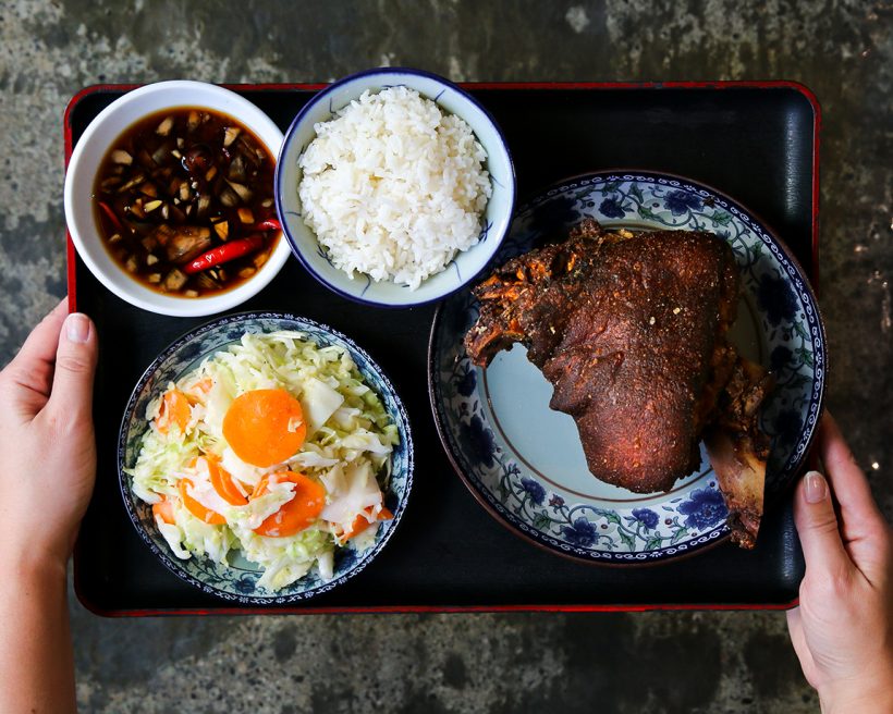 A tray with barbecue pork, rice, salads, and sauce