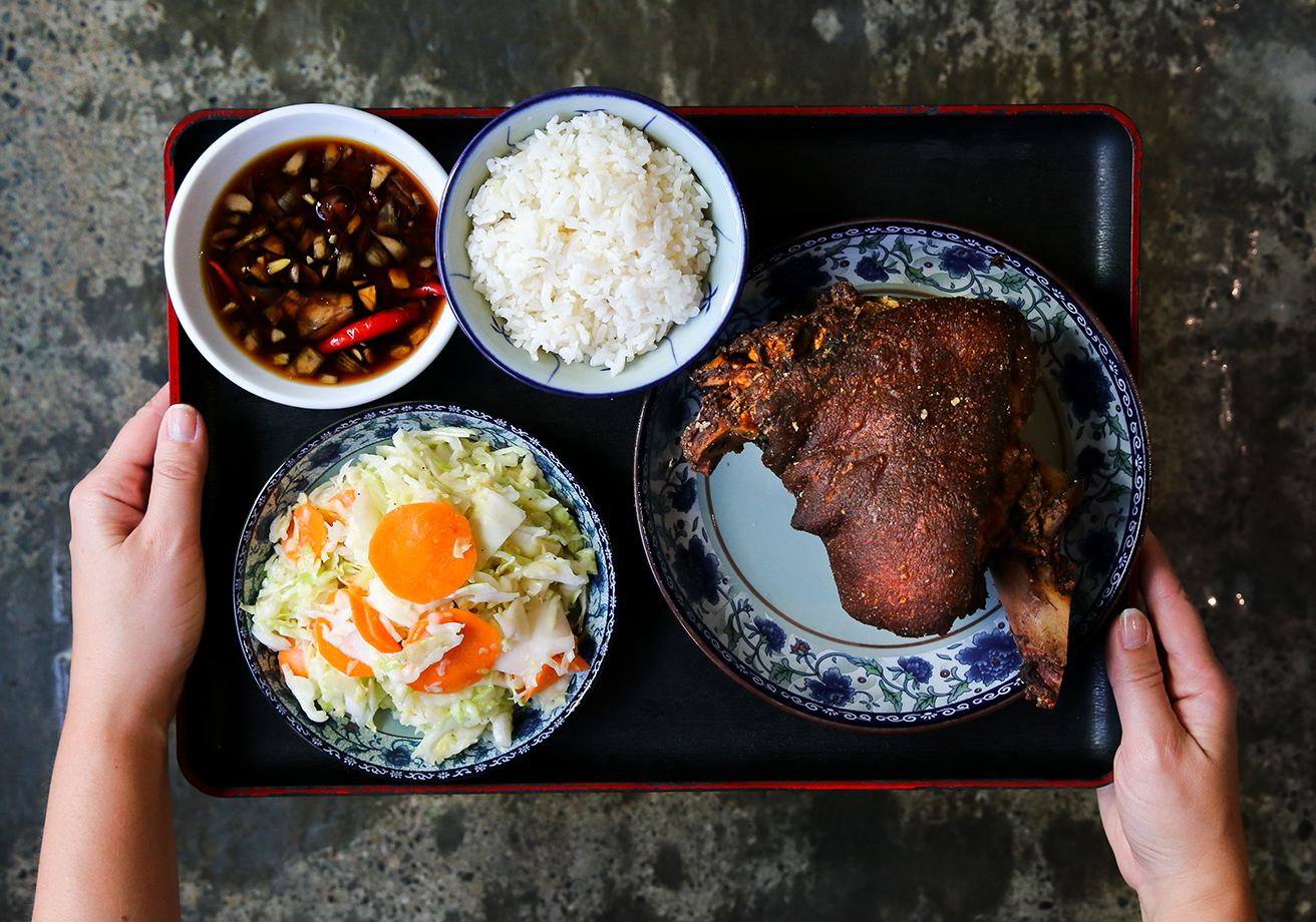 A tray with barbecue pork, rice, salads, and sauce