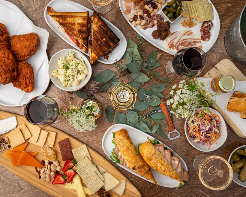 A spread of dishes including fried chicken, charcuterie, and sandwiches