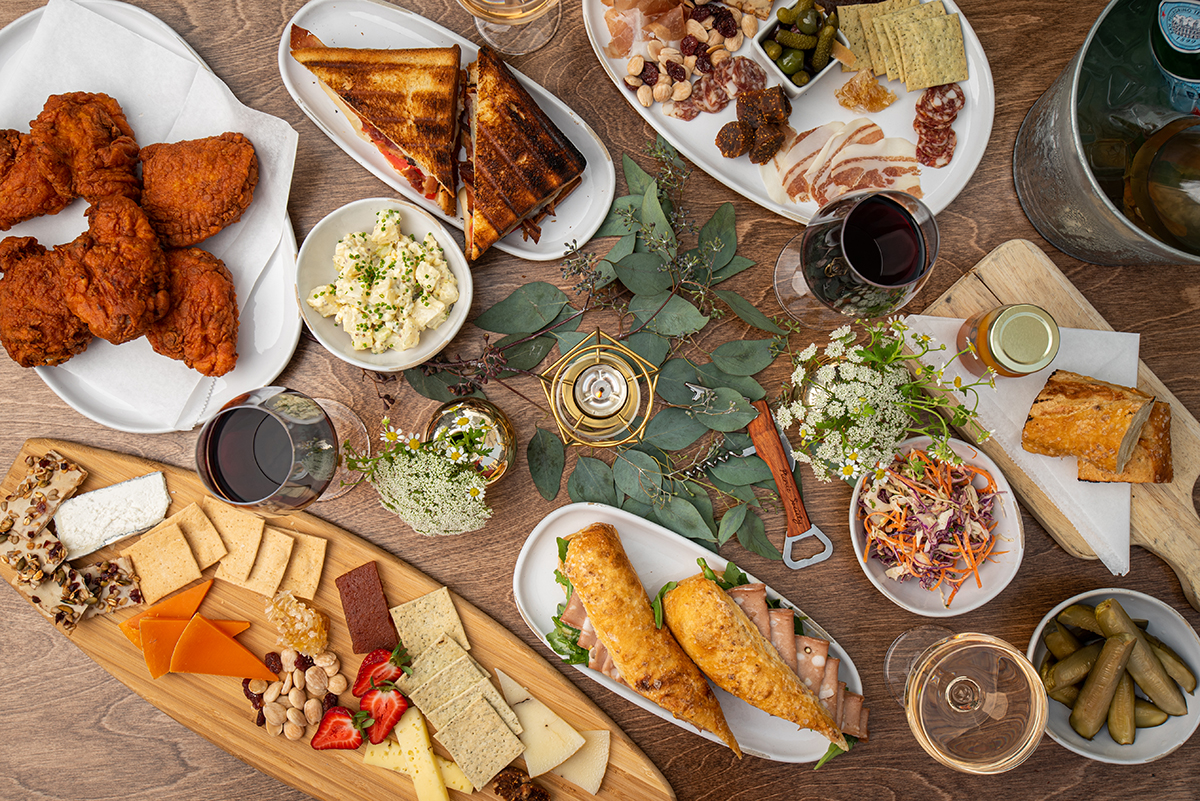 A spread of dishes including fried chicken, charcuterie, and sandwiches