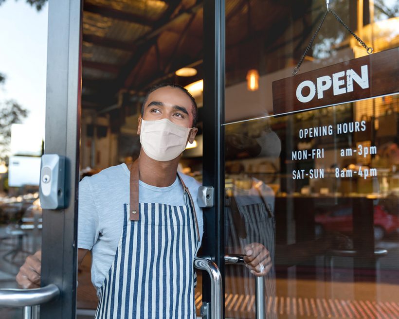 A masked restaurant worker opens the door