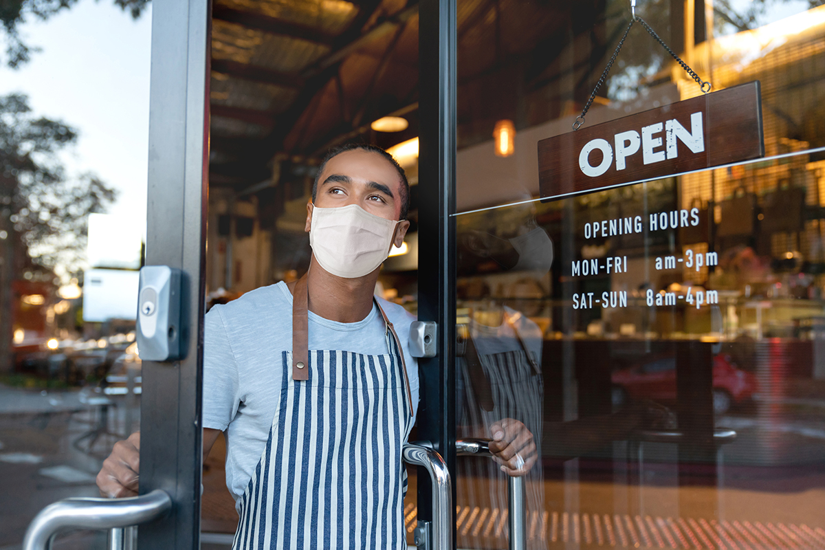 A masked restaurant worker opens the door