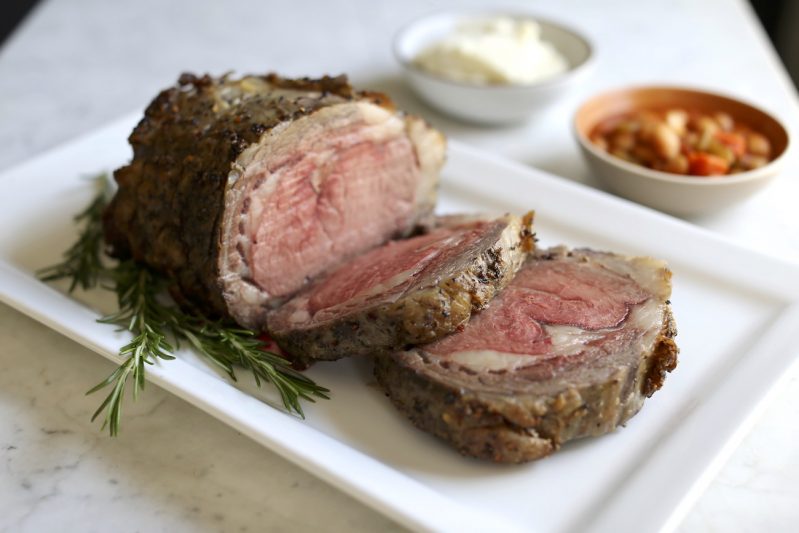 A plate of prime rib with condiments in the background