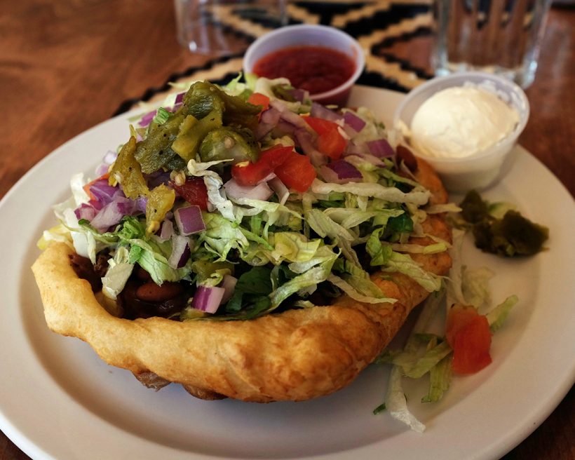 Frybread topped with lettuce, tomatoes, beans, and more