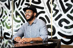 Kwame Onwuachie sits a table smiling