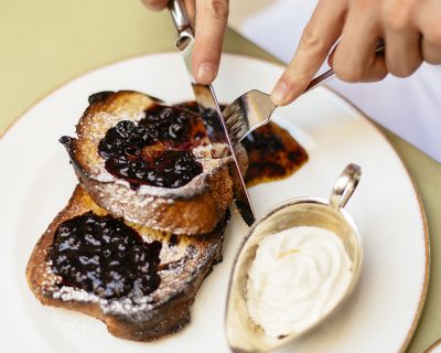 Cutting into French toast with jam