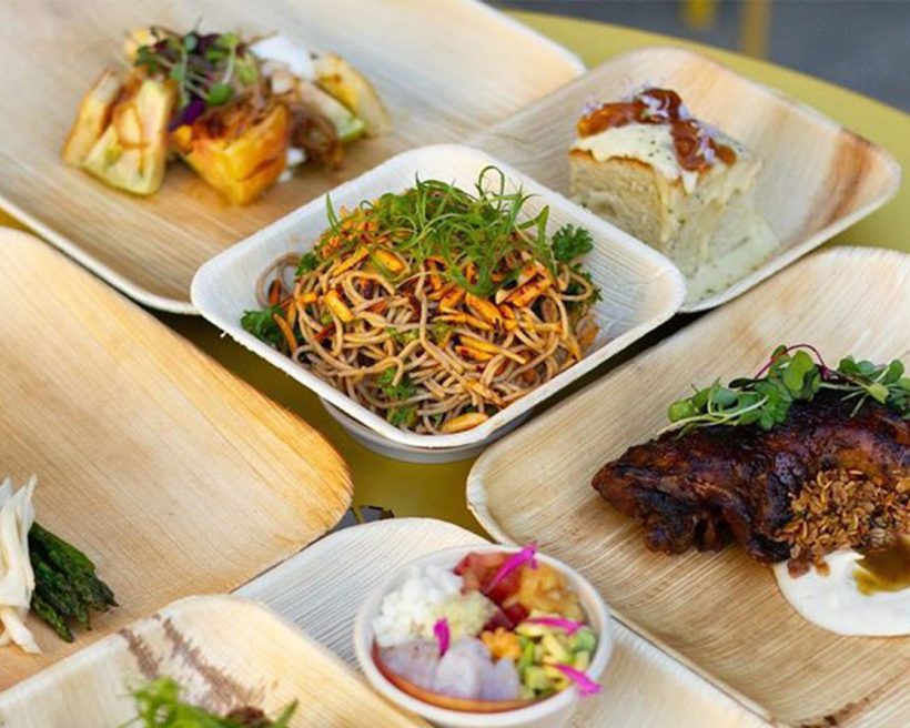 A variety of food on disposable takeout plates sits on a table