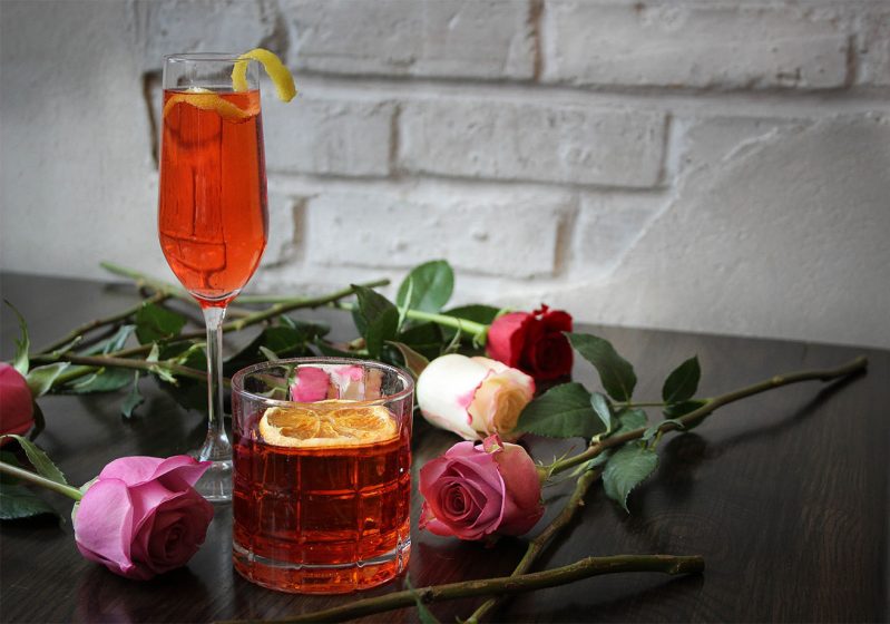 Two cocktails on a table with roses