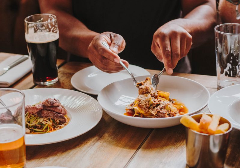 A person using silverware to pick up pasta
