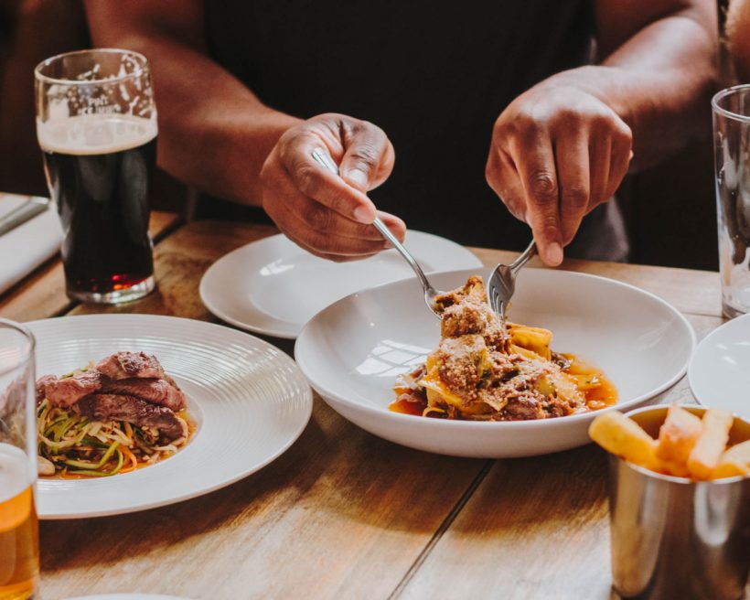 A person using silverware to pick up pasta