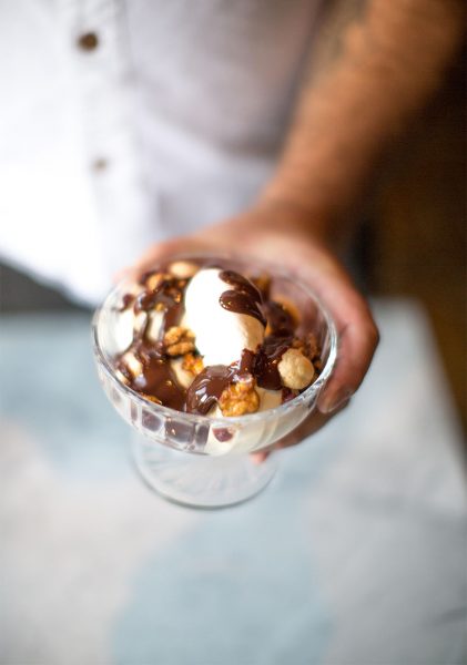 Ice cream covered with chocolate syrup and nuts in a glass