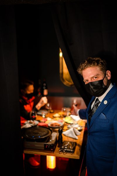 A server holds open the curtain to an outdoor cabana.