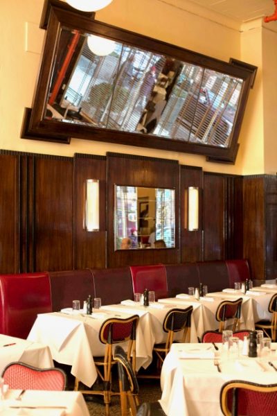 White table cloths and red leather chairs against a wood paneled wall.