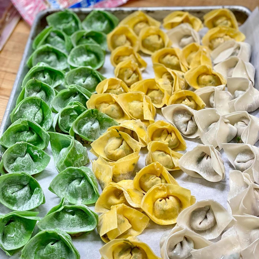 Green, yellow, and white wontons on a sheet tray