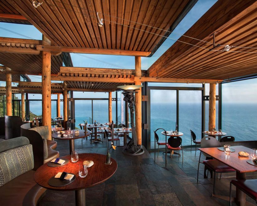 The enclosed glass dining room with sweeping Pacific Ocean views at Sierra Mar at the Post Ranch Inn in Big Sur, California
