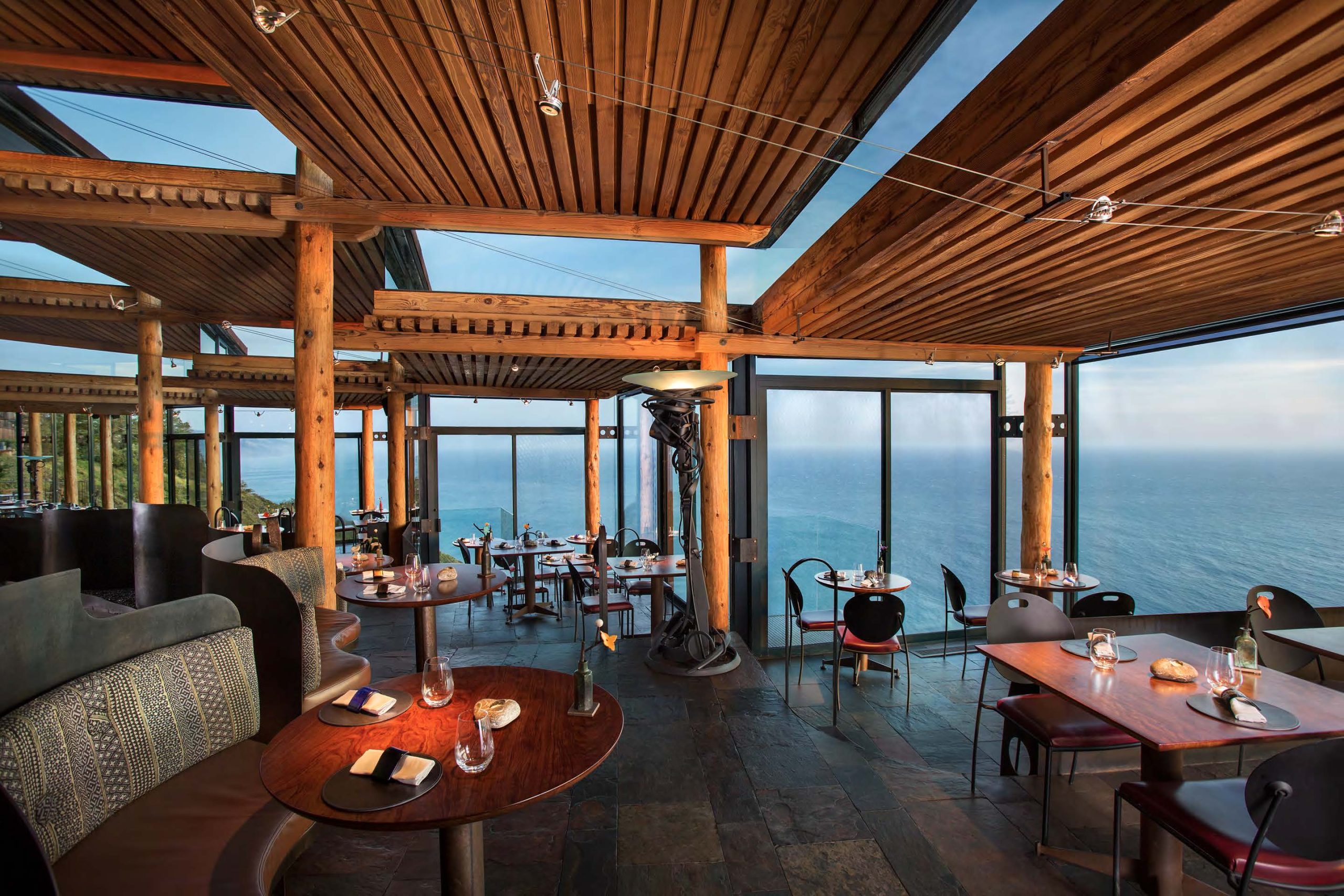 The enclosed glass dining room with sweeping Pacific Ocean views at Sierra Mar at the Post Ranch Inn in Big Sur, California