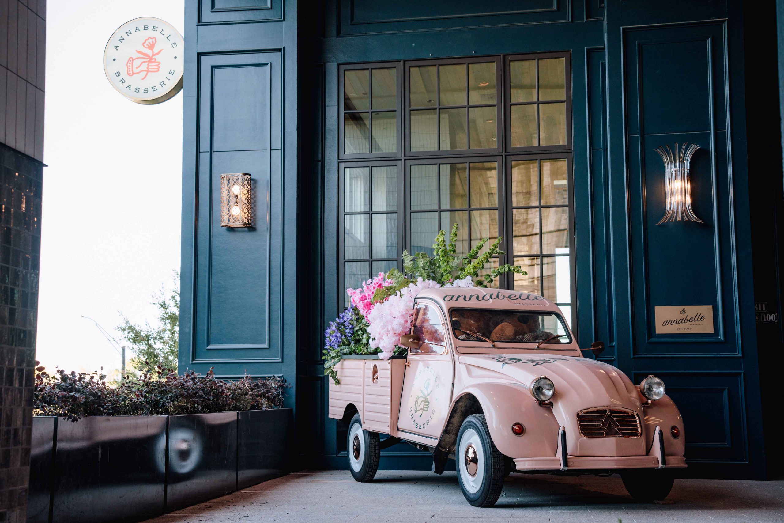 A pink Citroën truck decked with flowers by the entrance at Annabelle Brasserie in Houston