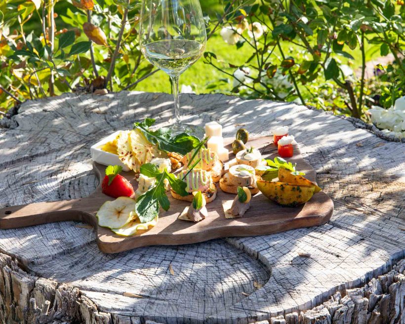 A charcuterie board with cheeses and vegetables sits on a tree stump at Quiessence at The Farm at South Mountain in Phoenix, Arizona.