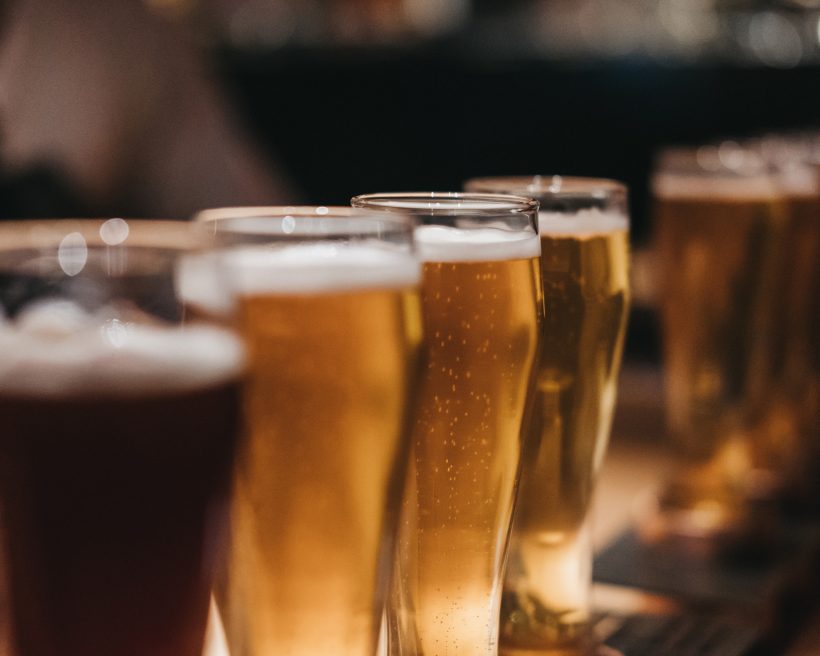 Close up of a rack of different kinds of beers, dark to light, on a table.
