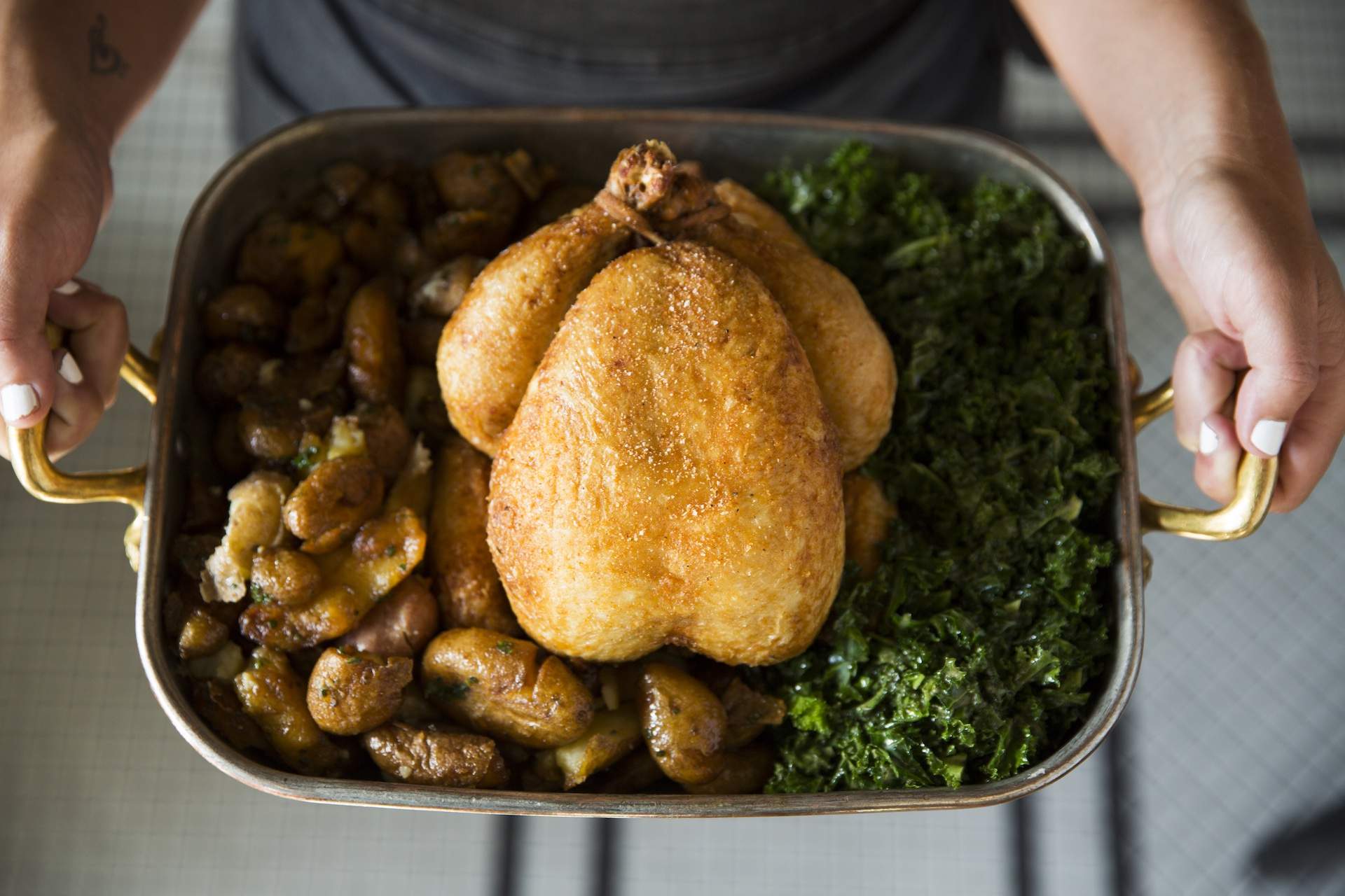 The whole chicken for two served with crispy potatoes, kale, and grilled onion vinaigrette at Josephine in 12 South.