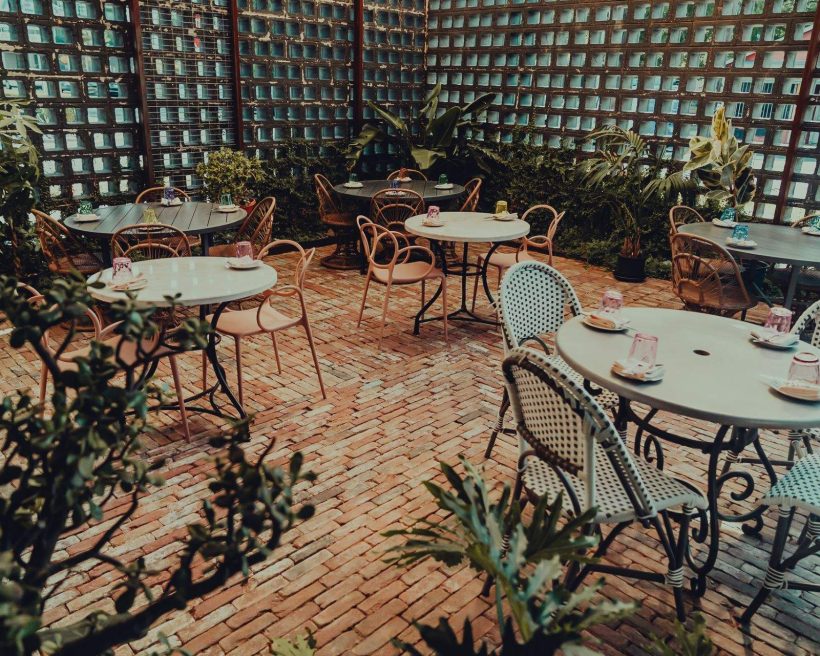 Plants surround the small round tables on the cozy patio at 1417 French Bistro in Austin