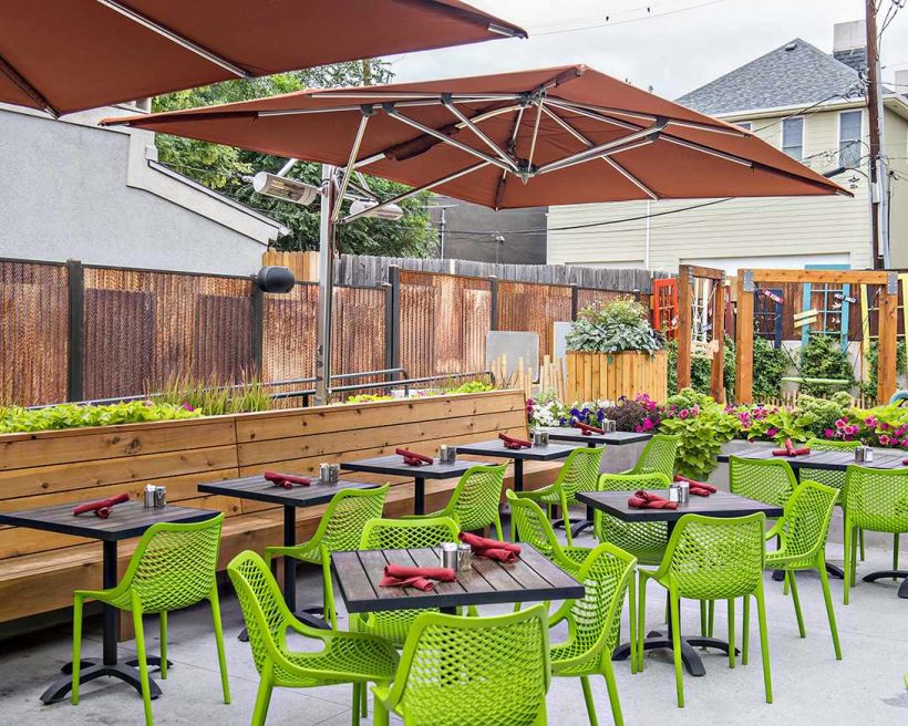 Lime-green chairs and wooden tables make up the large patio at Acova in Denver.