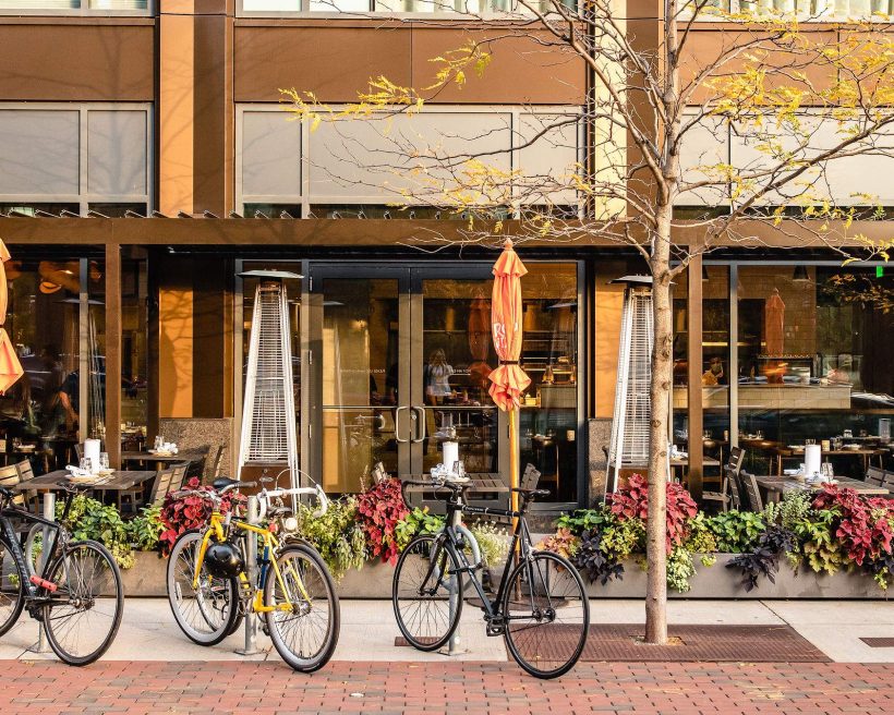 Streetside tables, orange umbrellas, and greenery at Bar Mezzana in Boston