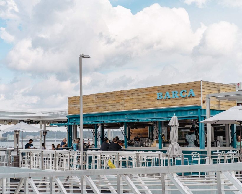 A teal-colored shipping container facade makes up the exterior to BARCA Wine Bar and Pier in the Old Town Alexandria
