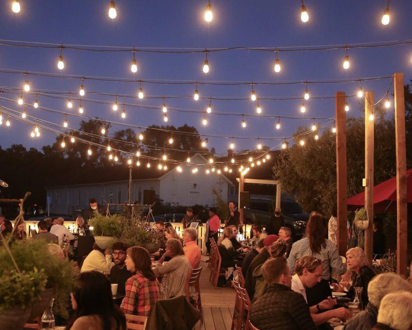 Twinkling lights illuminate the wraparound porch at Presidio Social Club in San Francisco