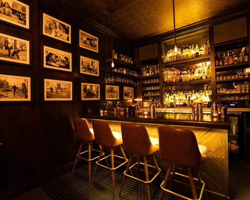 A dark and moody bar with drop lights and framed black-and-white photographs at The Alderman in Chicago.