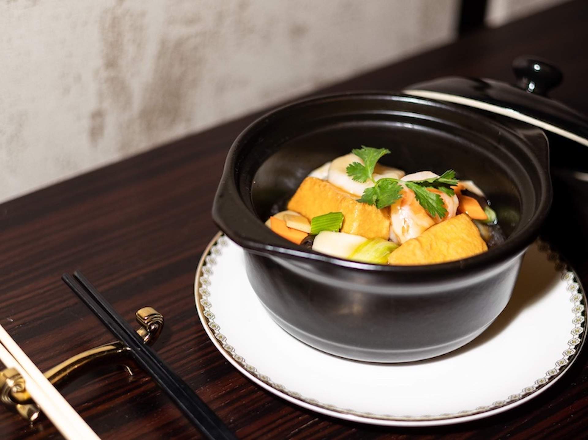 A tofu and seafood stew placed in a black bowl at Genting Palace