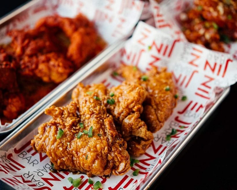 Deep yellow and orange pieces of fried chicken placed on trays