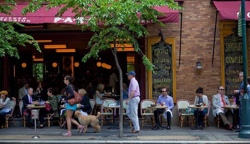 Diners on outdoor chairs under a maroon awning at Parc in Philadelphia