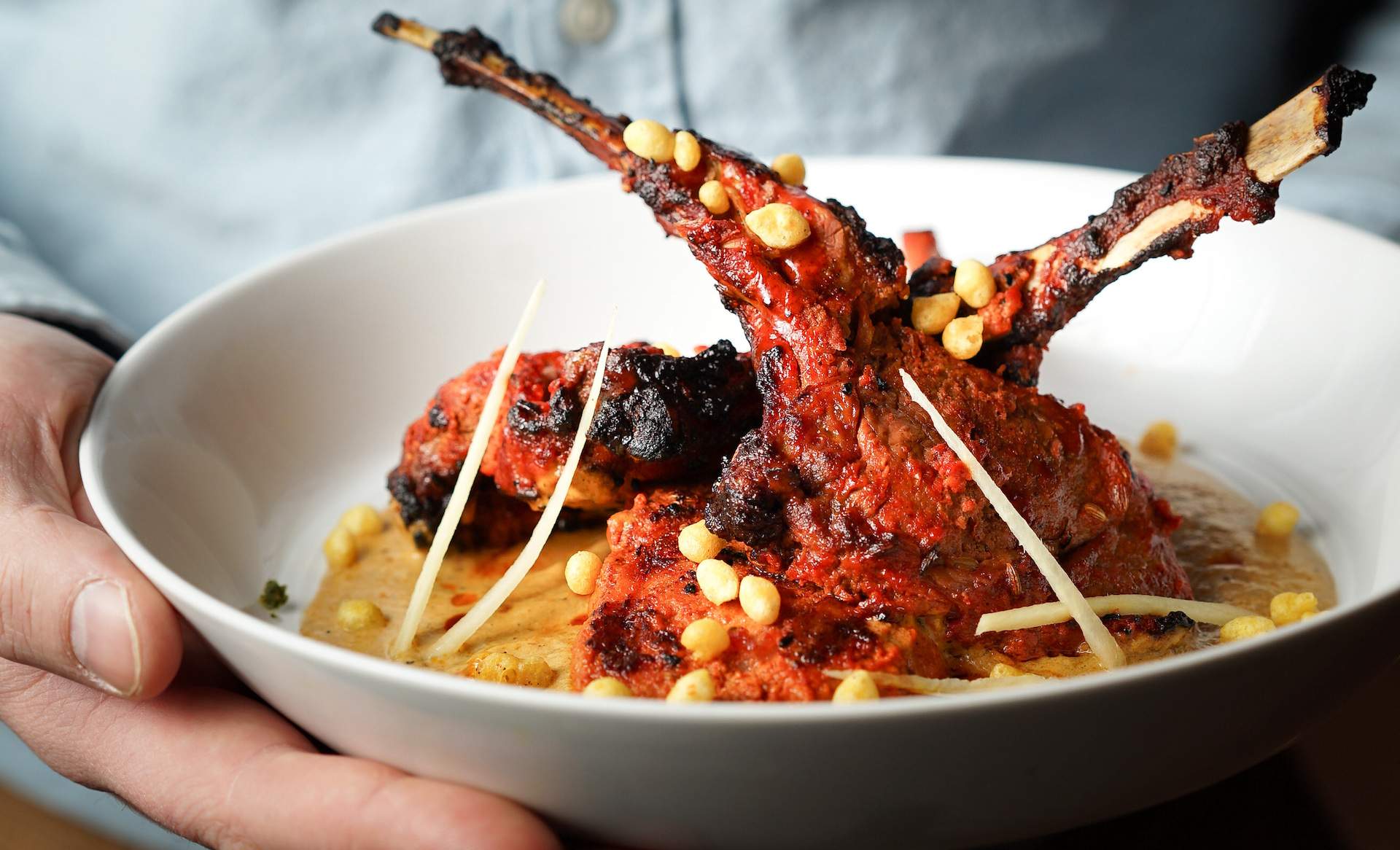 Two orange colored lamb chops placed on a bed of yellow puree.