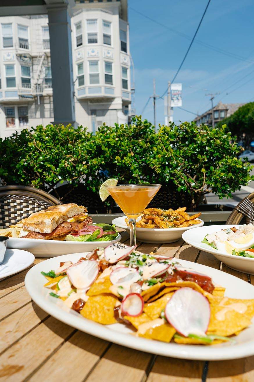 The brunch spread at Balboa Cafe in San Francisco includes chilaquiles and a house burger on baguette.