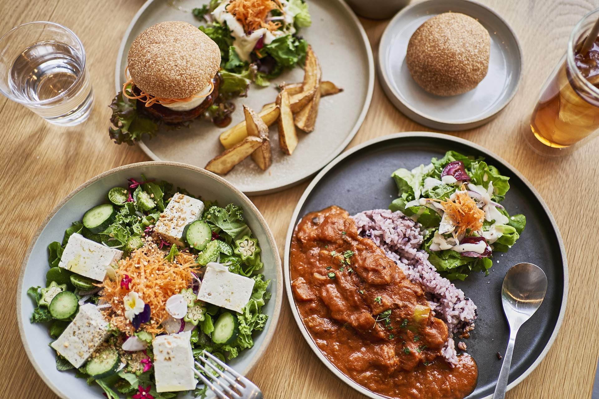 Several different plates of vegan food on a wooden background