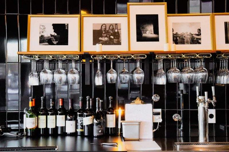 Wine glasses hang from a black-and-white bar at La Bouche in Denver
