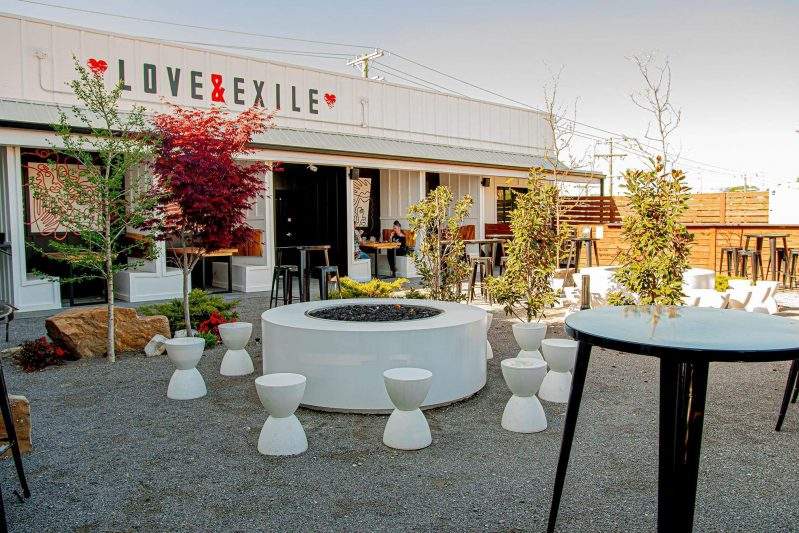 A fire pit is wreathed by white stools at the outdoor seating area at Love & Exile Winery and Bar in Nashville.