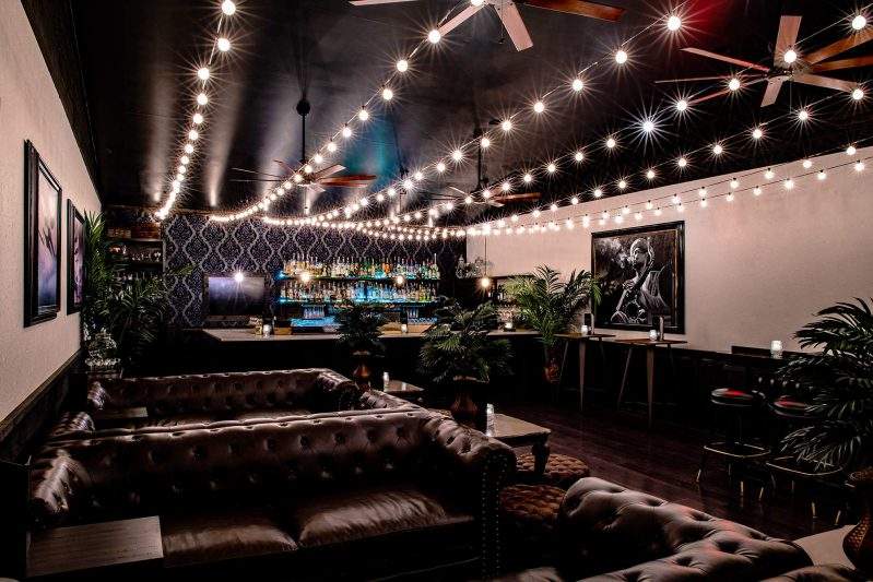 Brown leather couches and string lights make up the luxe mezzanine space at The Roosevelt Room in Austin.