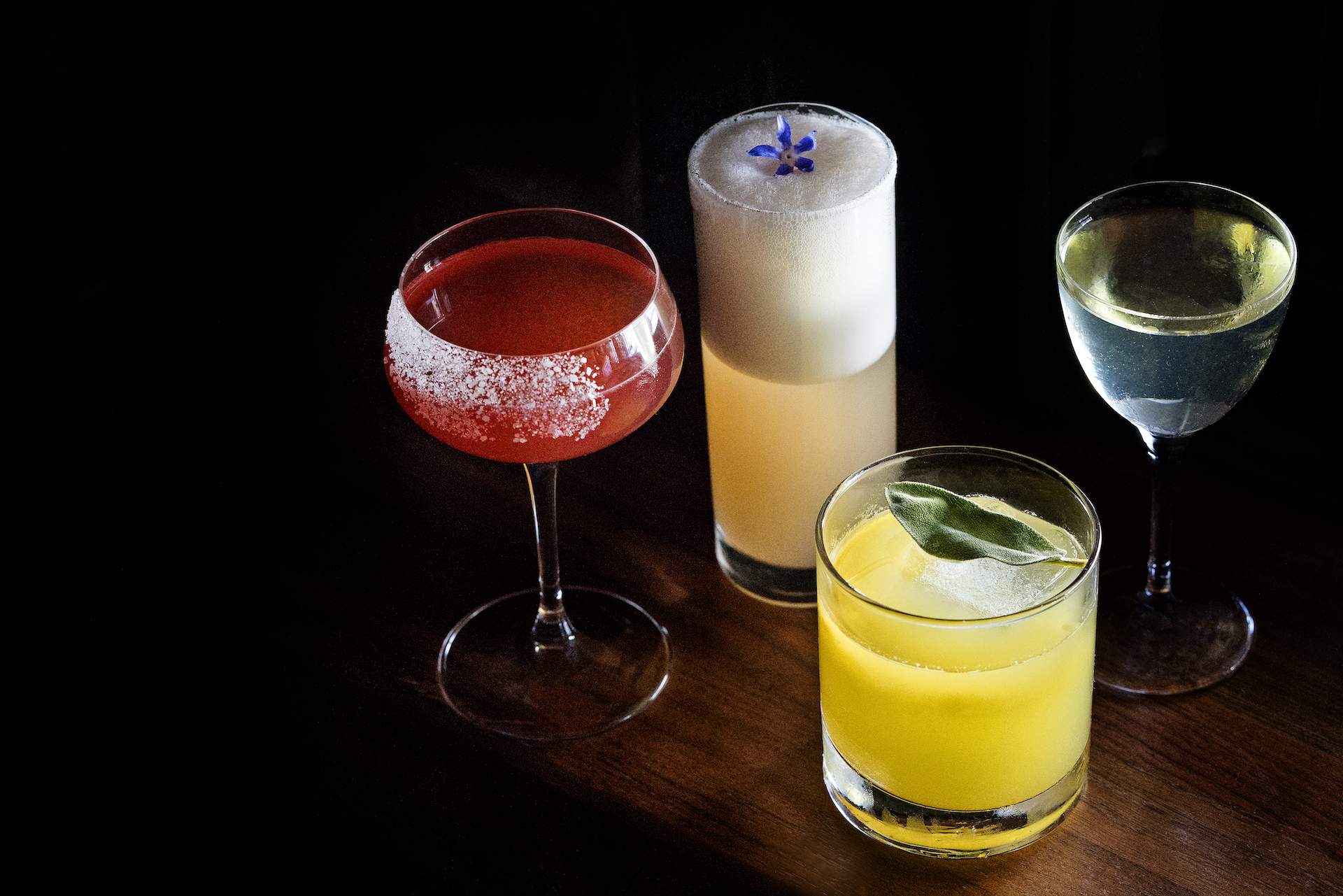 Four cocktails on a wooden surface