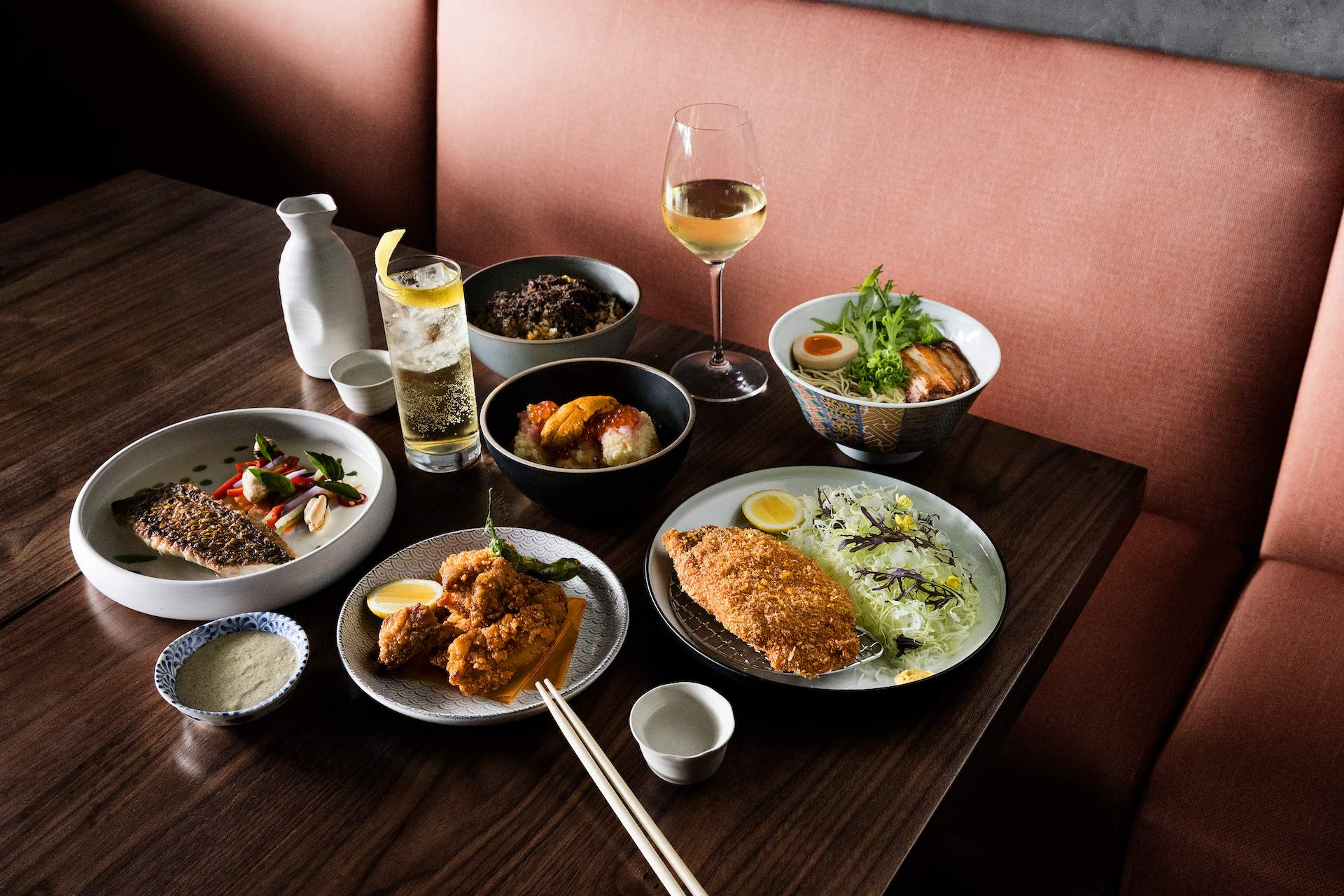Various plates of food on a wooden table with a pink