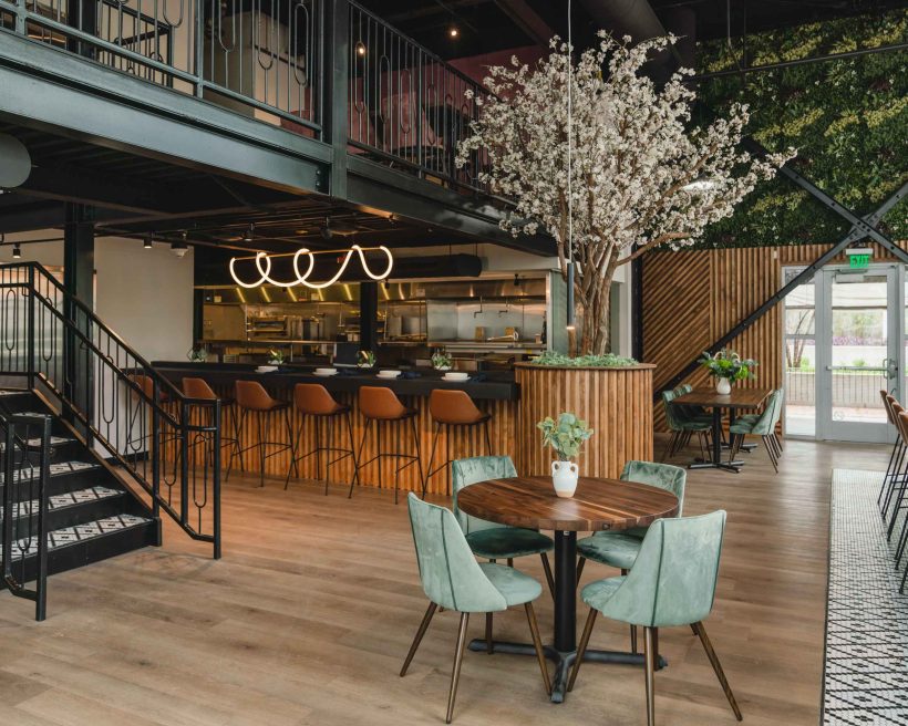 A cherry tree, velvet upholstery, and warm walnut tables make up the interiors at Ember Kitchen in Austin